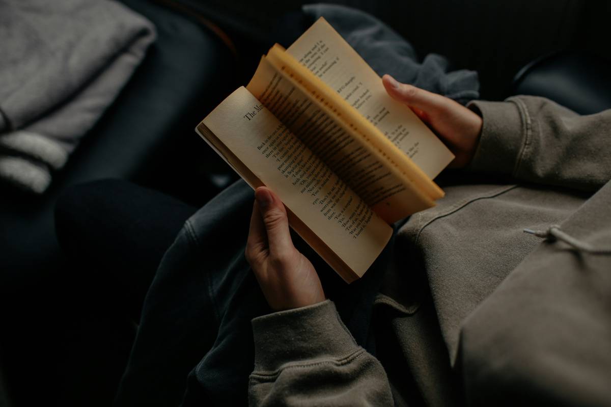 Person in a gray hoodie reading a book